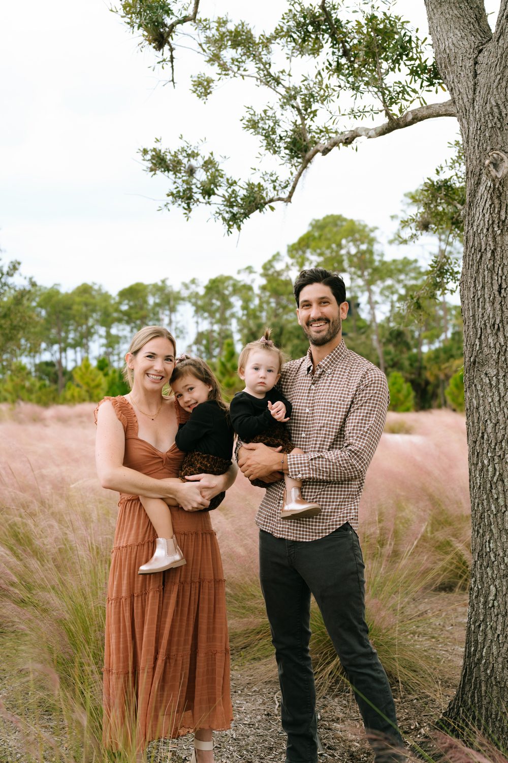 Co-founder Sam and his wife Lauren holding their daughters Maeve and Margaux in a field of tall pink grass